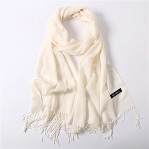 Detailed macro view of cream cashmere scarf with delicate tassel fringe and soft texture
