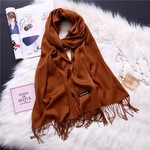 Detail shot of a caramel cashmere scarf with fringes and quality brand label