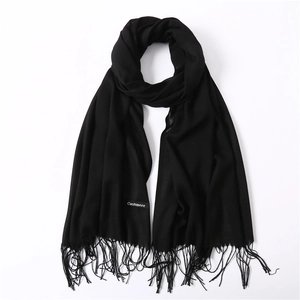 Detail shot of black cashmere scarf texture with soft fringe and sewn fabric label