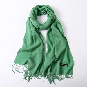 Detail of green cashmere scarf with delicate tassels showing soft fabric texture