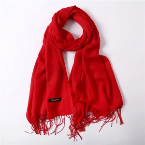 Detail shot of solid red cashmere scarf showing delicate fringe edges and soft texture