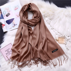 Detail shot of caramel cashmere scarf with tassels on elegant fashion background