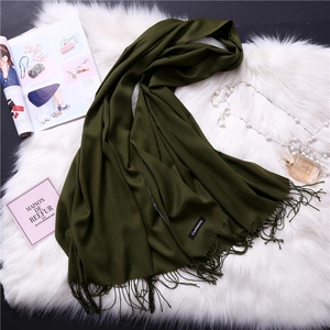 Close-up of dark green cashmere scarf with fringe, styled with luxury accessories