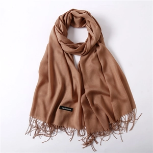 Detail of camel cashmere scarf featuring fine fringe edges and soft textile texture