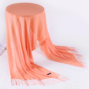 Close-up of light orange cashmere pashmina with long fringe details and fabric label