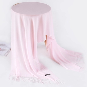 Detail of light pink cashmere scarf featuring elegant fringe and soft texture