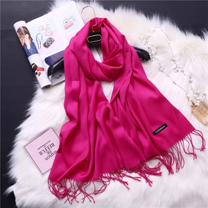 Detailed close-up of a magenta cashmere scarf with fringe and a sewn-on brand label