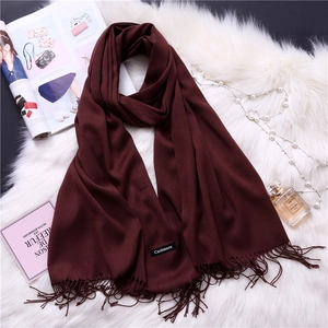 Detailed view of dark wine red cashmere scarf with fine fringe on a soft white fur background