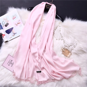 Detailed view of light pink cashmere scarf with fringe edges and brand label