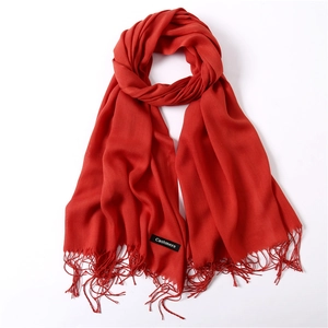 Detailed view of vermilion solid color scarf with cashmere label and fringe tassels