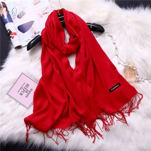 Close-up of a red cashmere scarf with fringe details on a soft faux fur background