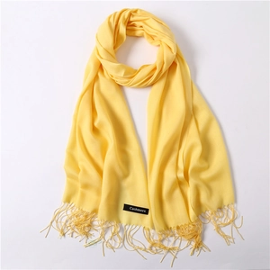 Detailed macro view of the yellow cashmere scarf edge with long fringe and fabric label