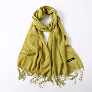Detail shot of vibrant mustard green scarf with soft fringe and Cashmere label