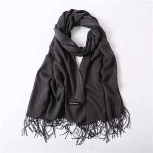 Detail of dark charcoal cashmere scarf with soft fringes and authentic woven label