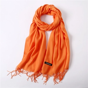 Detail of bright orange cashmere scarf with fine fringe tassels and brand label