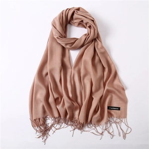 Close-up of beige cashmere shawl scarf with elegant fringe and branded label