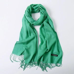 Solid bright green cashmere scarf with fine tassel fringe on a white background