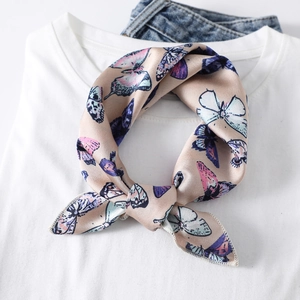 Close-up of silk neck scarf with colorful butterfly patterns tied on a white t-shirt