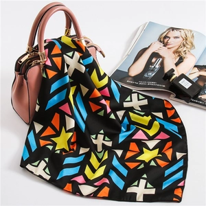 Close-up of silk satin square scarf with colorful geometric patterns on a luxury handbag