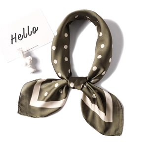 Olive green satin neckerchief with white polka dots tied in a bow on a white background