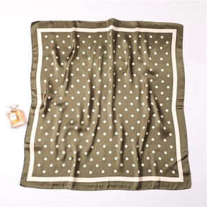 Close-up of olive green satin silk scarf with white polka dots and elegant cream border