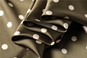 Macro detail of dark green silk satin scarf featuring classic white polka dots texture
