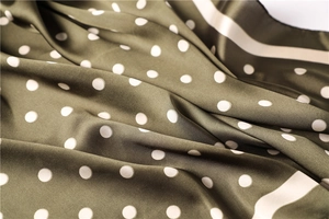 Detailed view of olive green satin scarf fabric with white polka dots and stripe edge