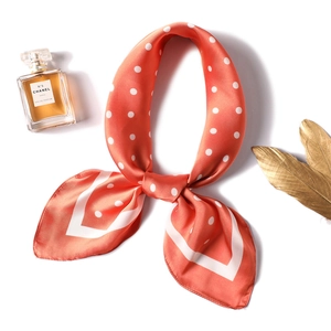 Close-up of silk satin neck scarf in coral orange with white polka dot pattern