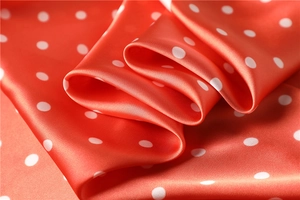 Detail of red satin scarf with white polka dot pattern and smooth silky texture