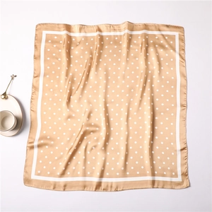 Champagne satin silk scarf with white polka dots laid next to a coffee cup