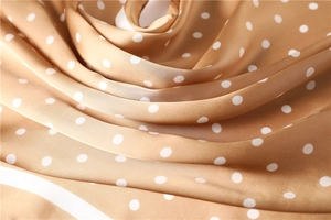 Macro shot of polka dot silk satin scarf fabric with champagne gold sheen and soft drape