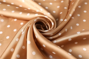 Macro detail of champagne gold satin scarf with elegant white polka dot pattern textures