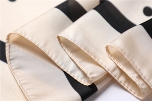 Detailed close-up of smooth satin fabric with polka dots and fine machine-stitched edges