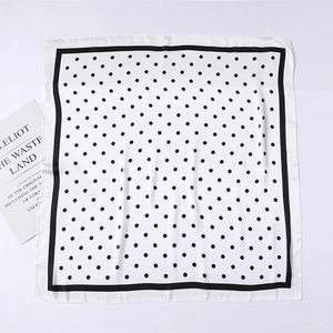 Close-up of elegant white silk scarf with black polka dots and border design