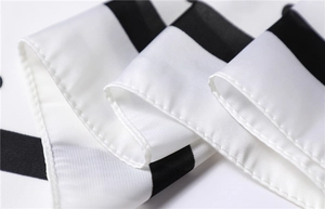 Macro detail of the fine rolled hem and smooth satin texture on the black and white scarf