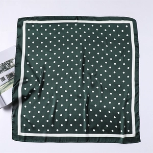 Close-up of dark green satin scarf featuring classic white polka dots and smooth texture