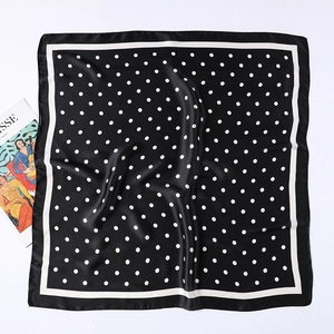 Detail of silk-satin square scarf featuring classic white polka dots on black background