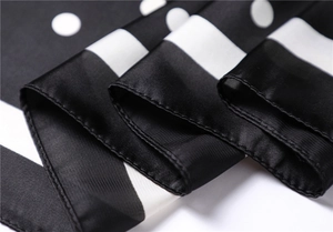Close-up of silky polka dot scarf showing detailed rolled hem and smooth satin texture