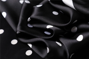 Detailed close-up of glossy satin silk scarf with elegant white polka dots on black