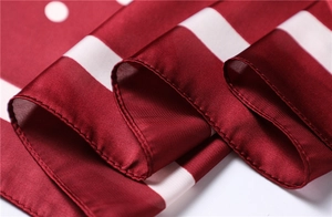 Detailed close-up of premium satin scarf fabric showing red polka dots and smooth texture