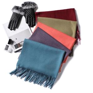 Close-up of assorted cashmere-like scarves with fringe and quilted leather gloves