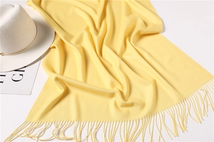 Close-up of yellow cashmere-feel scarf showing soft knit texture and long tassel fringe