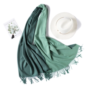 Detail of two-tone green cashmere scarf with fine fringe trim and elegant texture