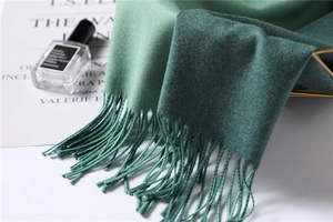 Detailed close-up of soft two-tone cashmere scarf in mint and forest green with tassels