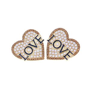 Détail de boucles d'oreilles cœur avec perles blanches, cristaux ambrés et lettres LOVE