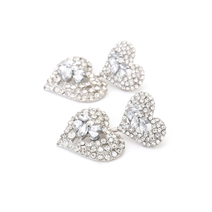 Vue macro de boucles d'oreilles cœur argentées multicouches avec strass brillants