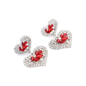 Détail macro de boucles d'oreilles cœur argentées avec strass et pierres marquises rouges
