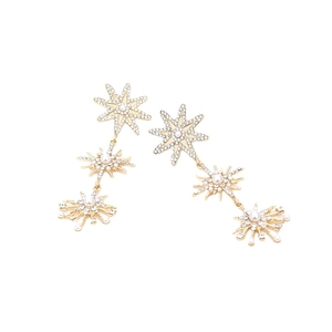 Exaggerated golden star drop earrings with pearls and rhinestones on white background