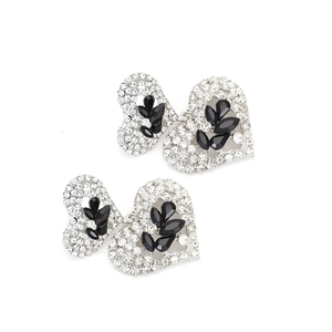 Détail de boucles d'oreilles pendantes en forme de cœur avec pavé de strass brillants