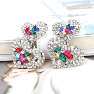Détail macro de boucles d'oreilles cœur multicouches avec pierres colorées et cristaux